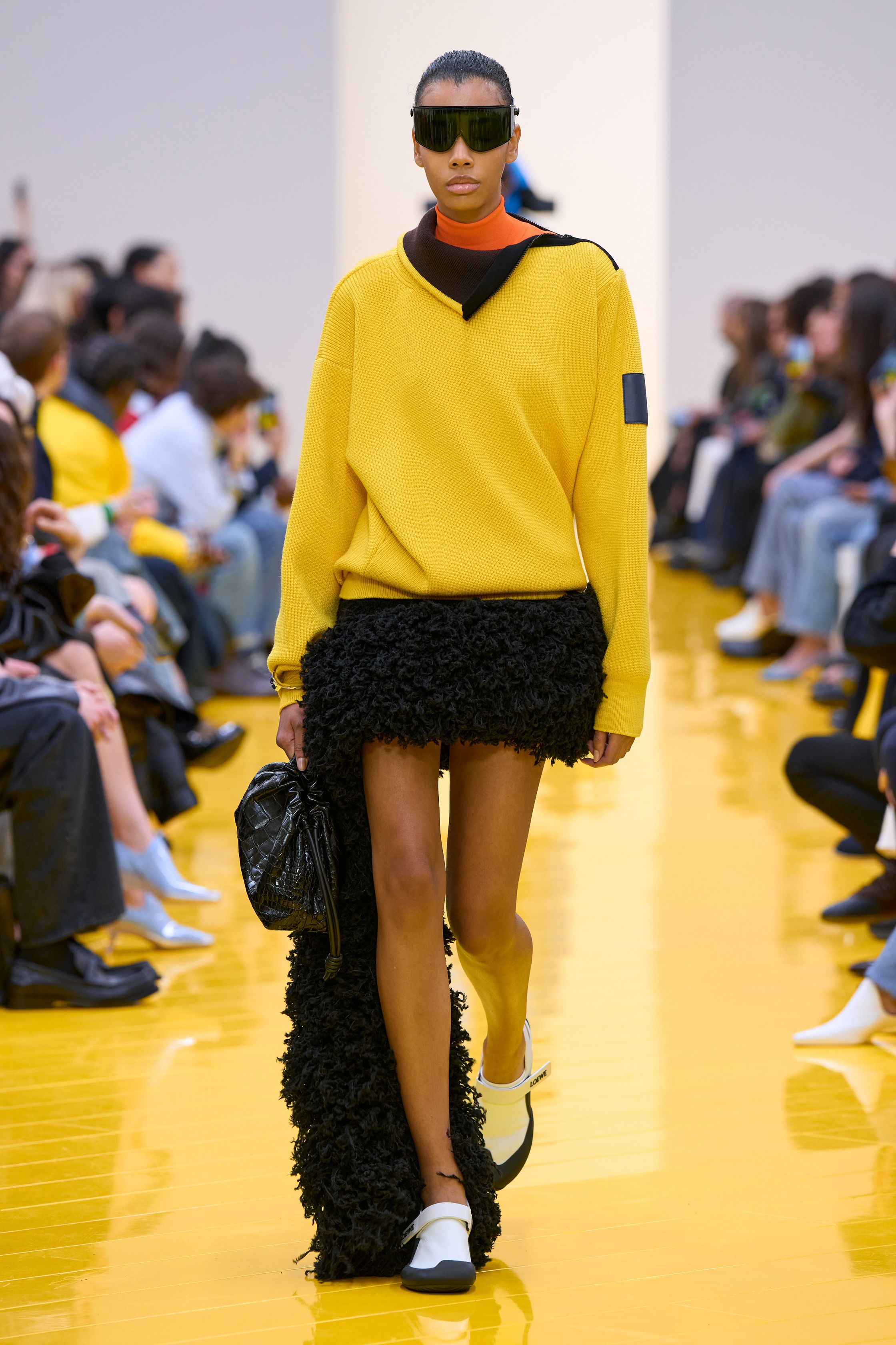 Jonathan Anderson 为 Loewe 带来一场充满艺术实验的秀：黄色地面与鲜明色彩形成强烈视觉舞台，极简廓形针织、雕塑化皮革外套、夸张毛绒结构和实验比例裙装共同构建一种“可穿戴雕塑”。从鲜黄、亮蓝到浓郁棕色毛绒，材质对比成为本季核心语言，既有幽默感也带有博物馆式艺术气质-顽石频道趋势研究